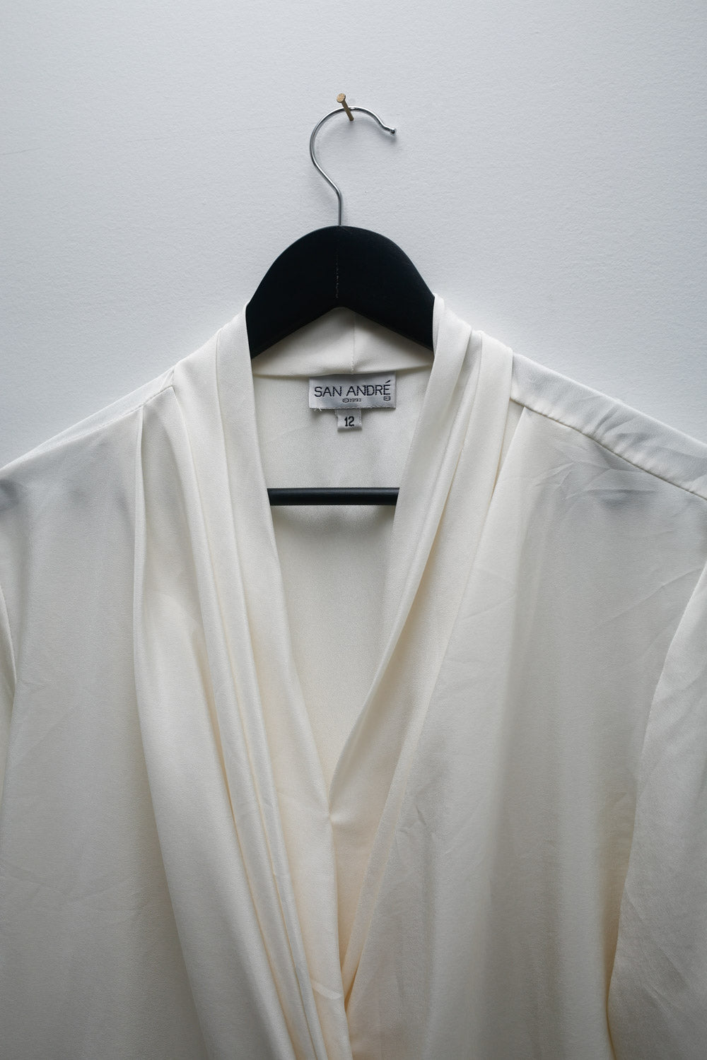 Vintage San André white satin blouse with draped wrap-style front, long sleeves, pleated neckline, and button closure.
